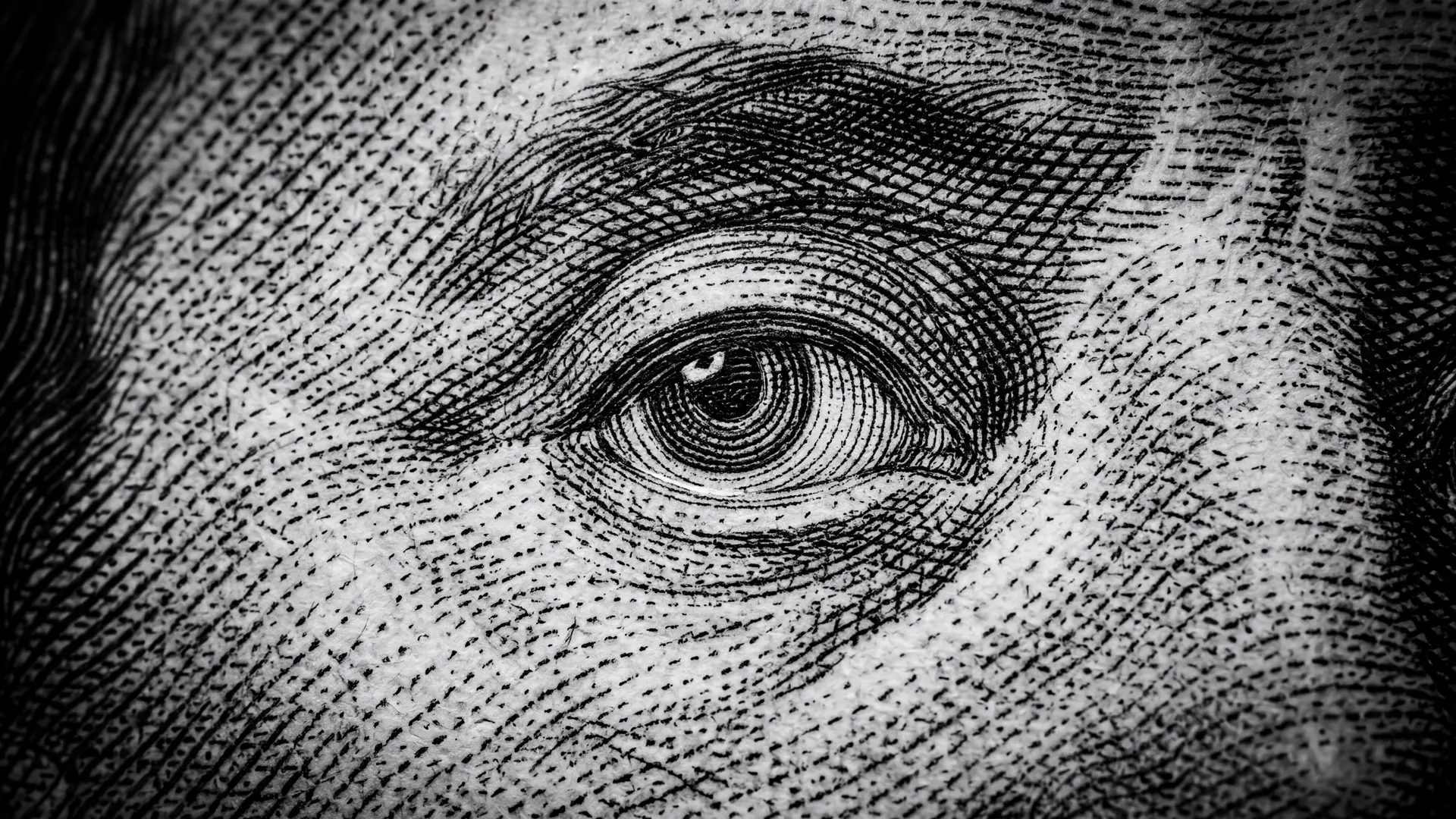 Close-up of the eye on a $100 bill, engraved in black and white